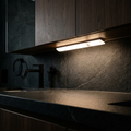GravN LED Mount light bar under a cabinet lighting a dark stone bathroom counter